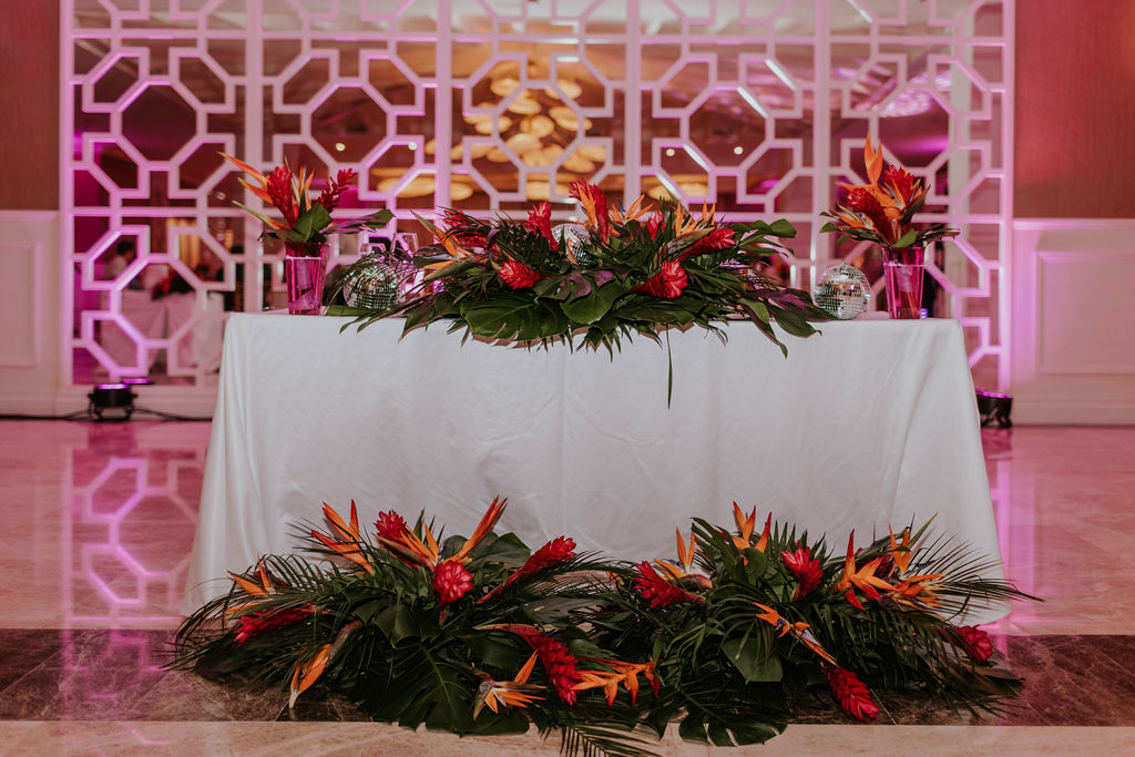 Tropical wedding sweetheart table decorated with vibrant florals at Majestic Elegance Costa Mujeres.