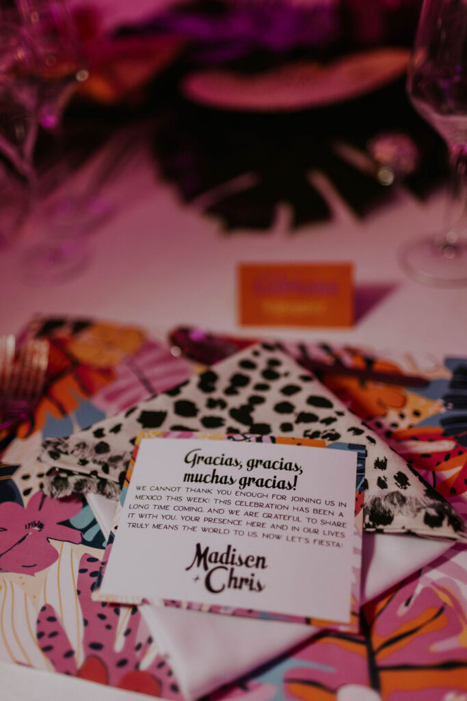 Custom wedding reception place setting featuring colorful tropical stationery and personalized thank-you note in Costa Mujeres.