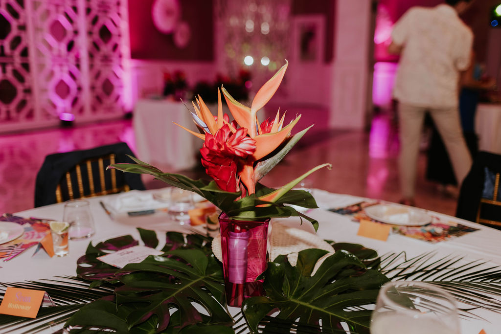 Tropical wedding centerpiece featuring bird of paradise flowers, ginger blooms, and monstera leaves at the reception.