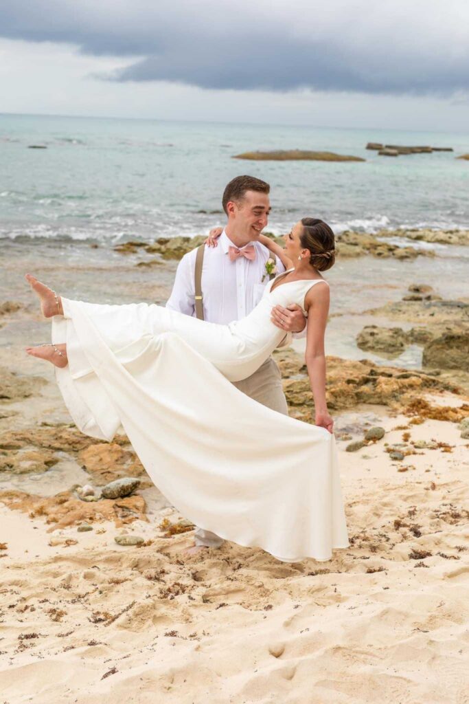 Newlyweds posing along the beach during their El Dorado Casitas Royale wedding