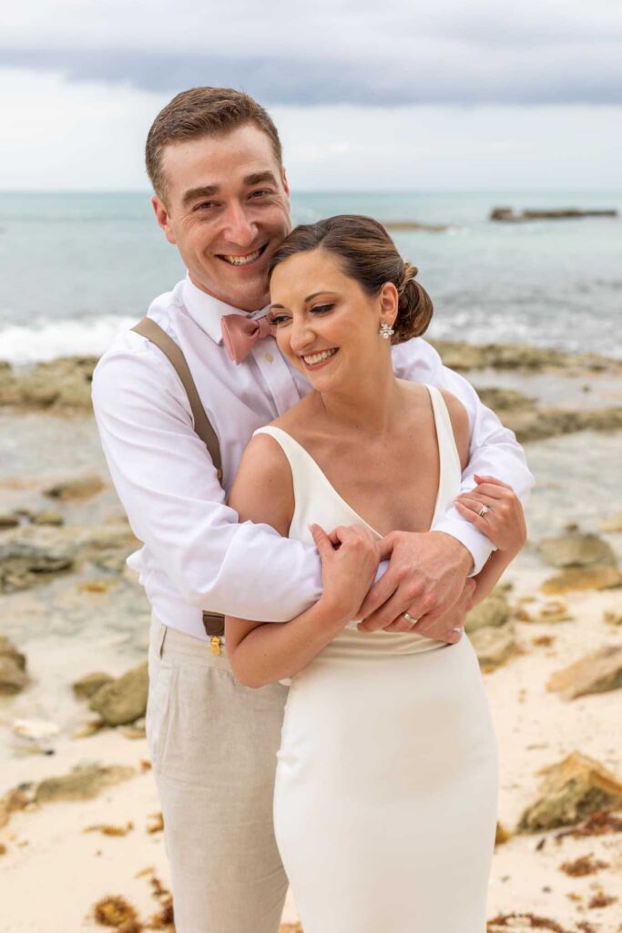 Bride and groom embracing on the beach at El Dorado Casitas Royale