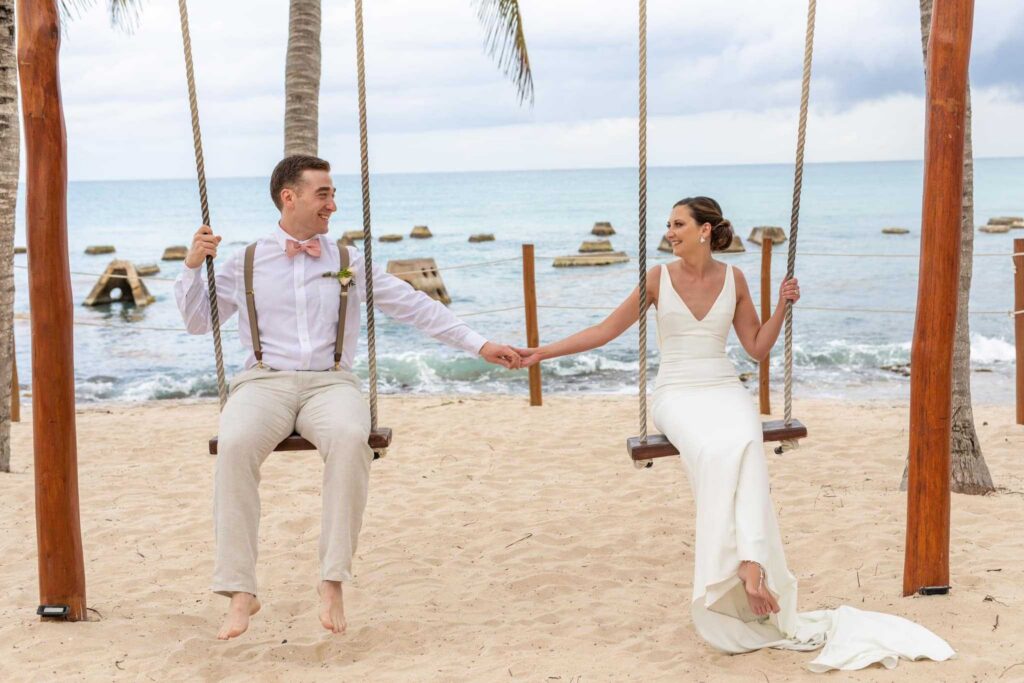 Bride and groom on beach swings during their destination wedding in Mexico