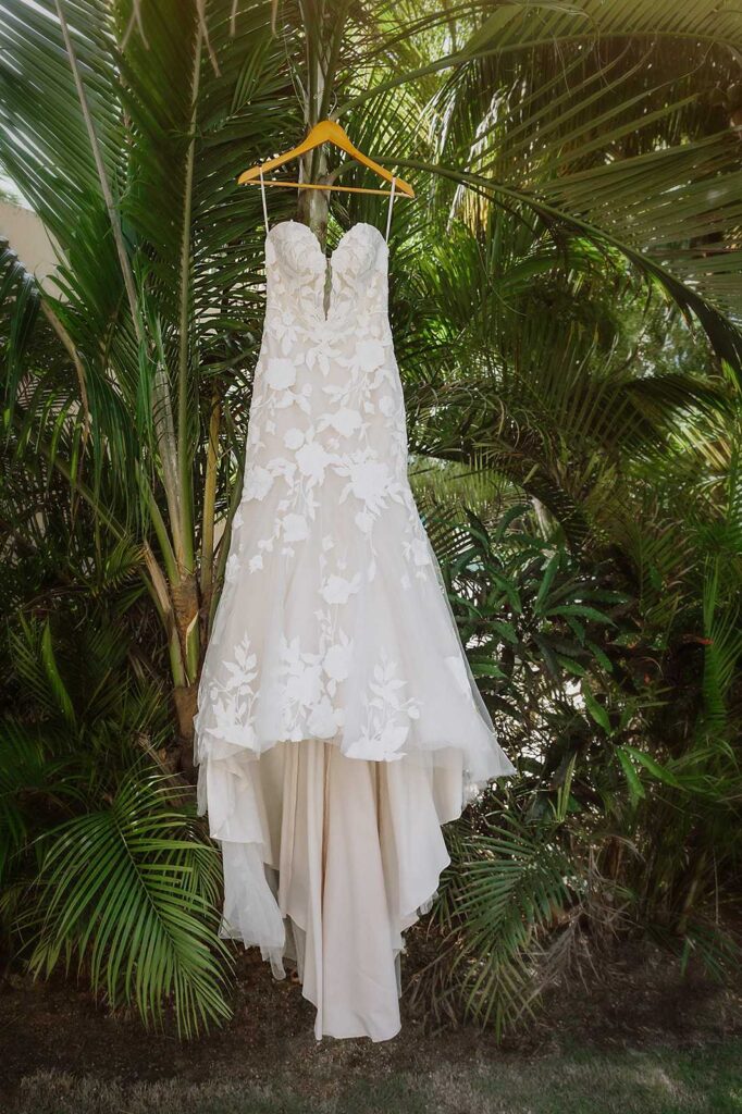 Wedding dress hanging among tropical palm trees at El Dorado Royale Resort Mexico