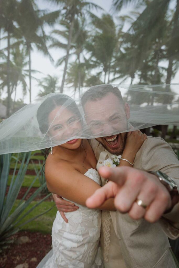 Fun candid wedding portrait beneath bride's veil at El Dorado Royale Mexico