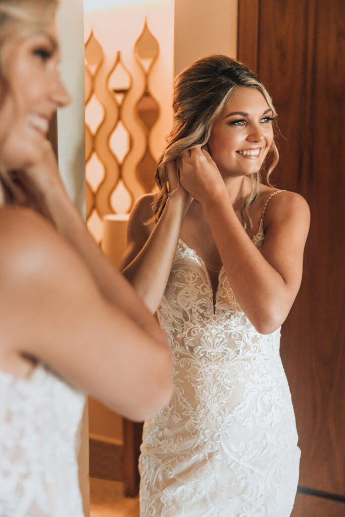 Bride putting on earrings while getting ready in her suite before a Secrets Maroma Beach Riviera Cancun wedding.
