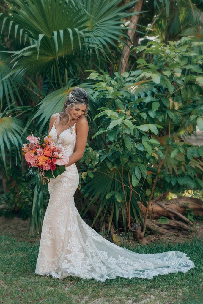 Bride holding a vibrant tropical bouquet surrounded by lush greenery at Secrets Maroma Beach Riviera Cancun.