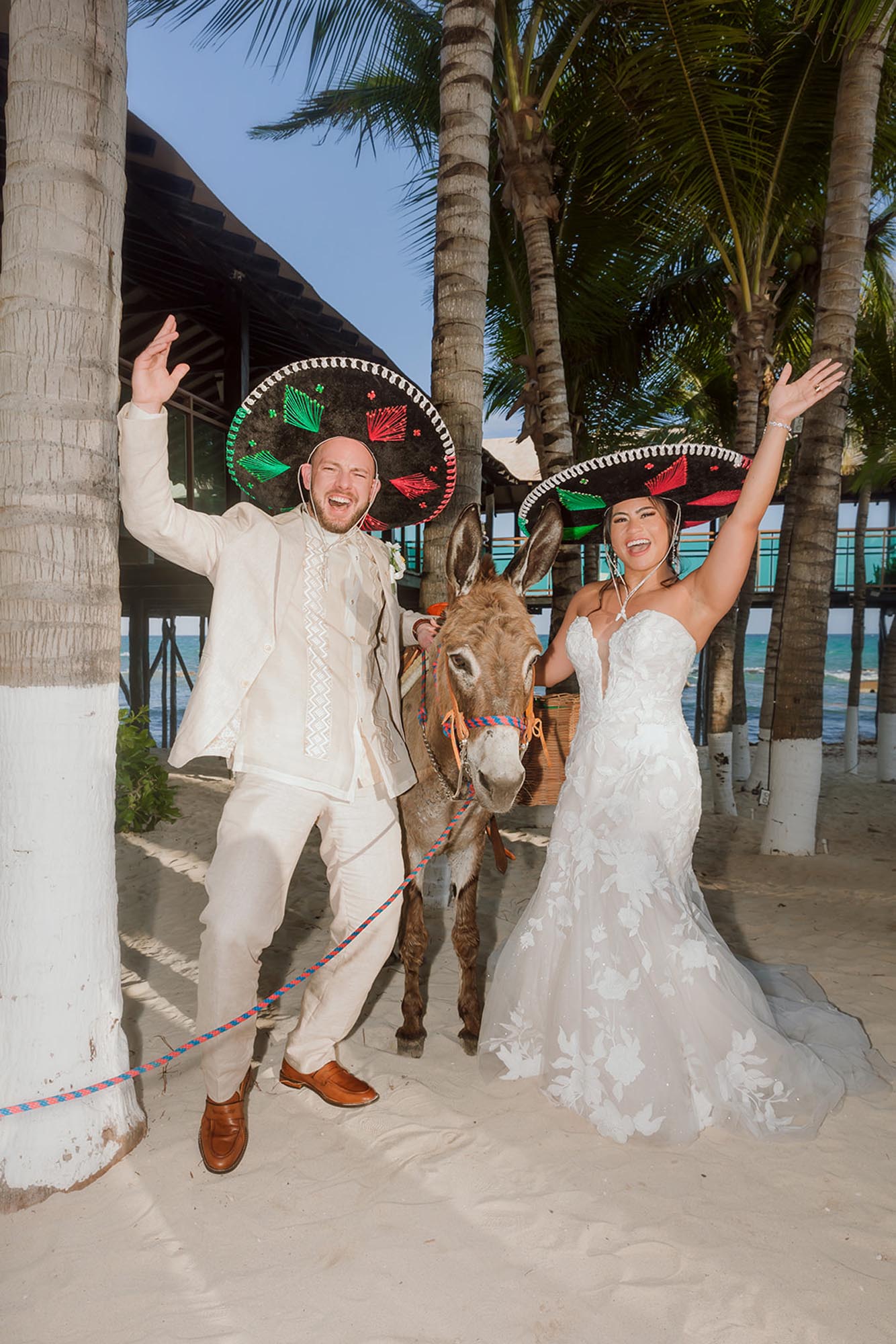 Couple wearing hats and posing with a donkey on their wedding day, showing why it matters to ​have a wedding planner for destination wedding