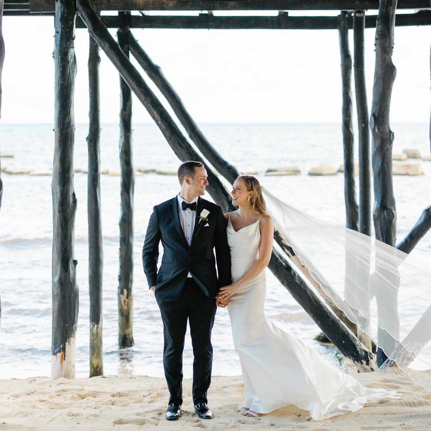 Bride and groom posing beneath the pier during their El Dorado Royale wedding in Riviera Maya