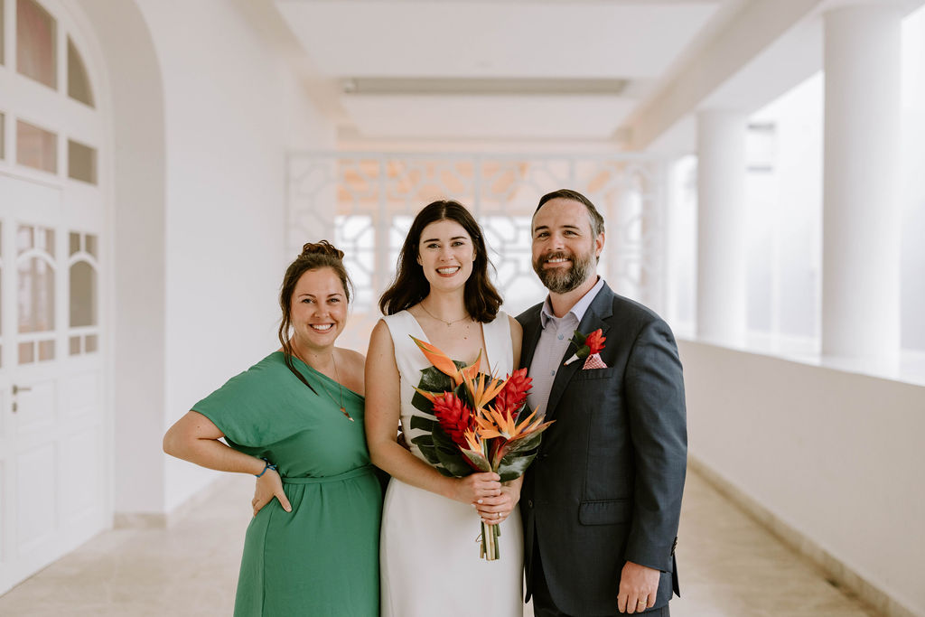Couple holding drinks and standing next to Morgan, one of the best travel agents specializing in destination weddings