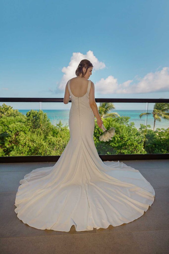 Bride overlooking the Caribbean Sea from a balcony at Unico 2087 before her Riviera Maya destination wedding