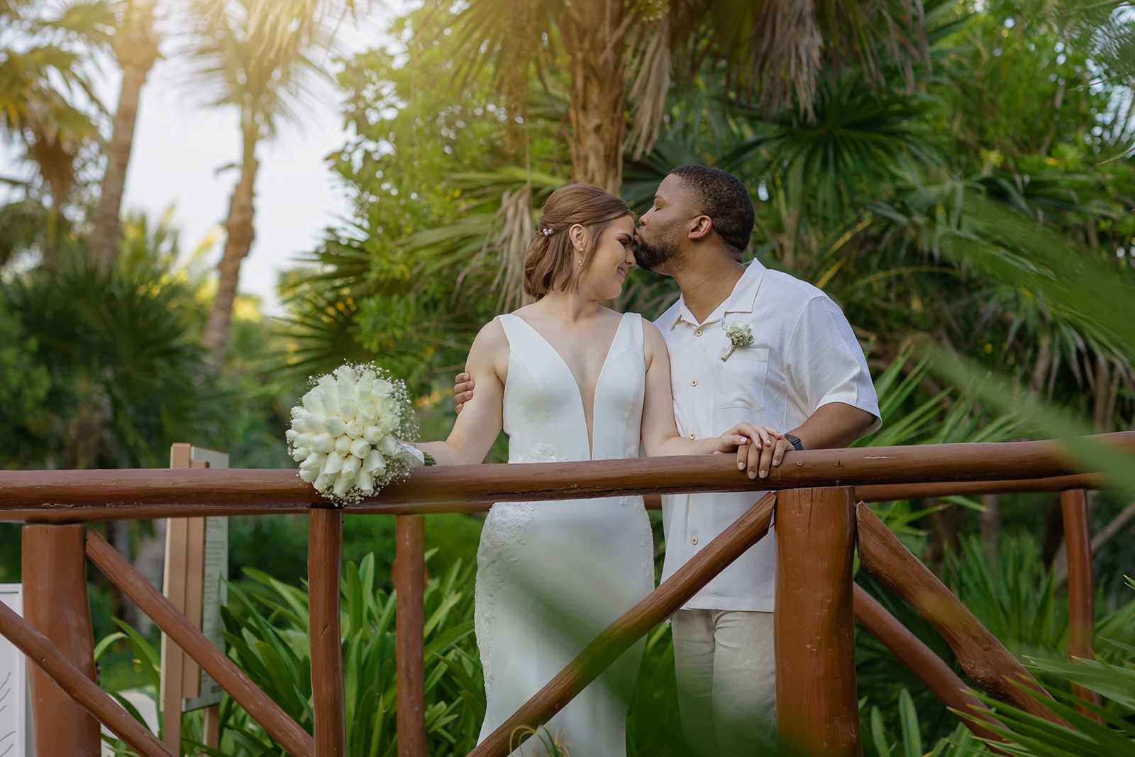 Groom kissing bride's forehead during an intimate Riviera Maya destination wedding