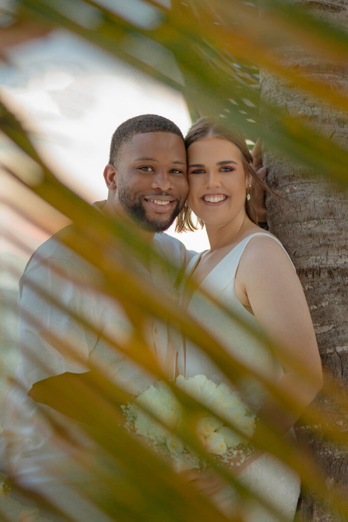 Newlyweds smiling together beneath palm trees at Unico 2087 Riviera Maya