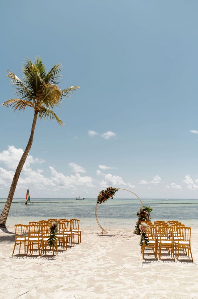 Empty beach ceremony setup with a round floral arch and gold chiavari chairs, a top destination wedding location in the Dominican Republic