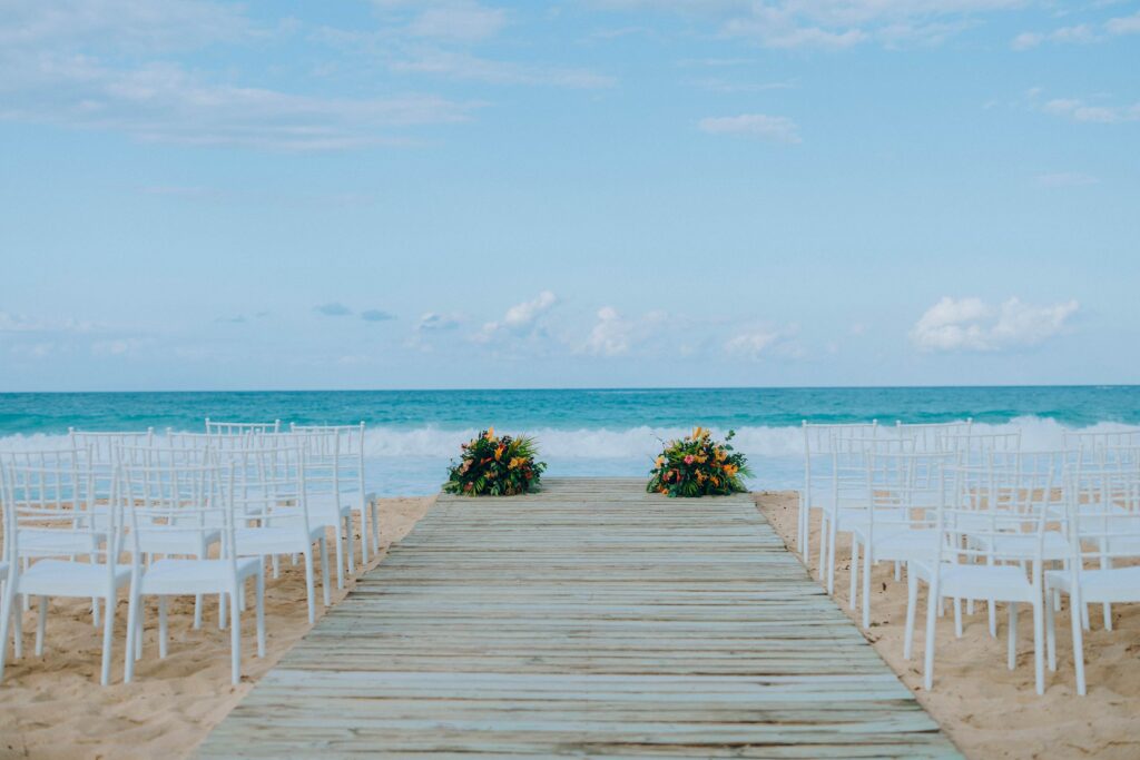 Wooden beach aisle lined with white chairs leading to the ocean at a Dominican Republic destination wedding