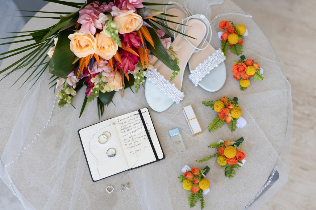 Bridal bouquet, wedding rings, vow book, shoes, and boutonnieres styled for a tropical destination wedding.