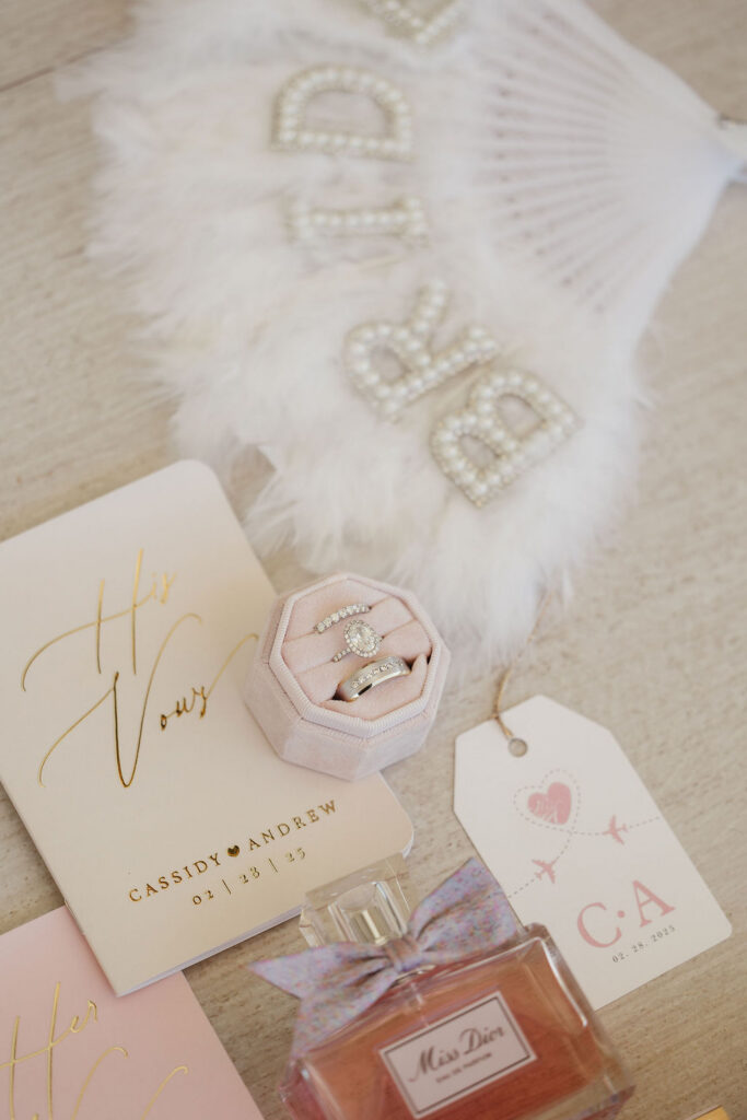 Wedding invitation suite with bridal rings, perfume, and accessories for a luxury destination wedding.
