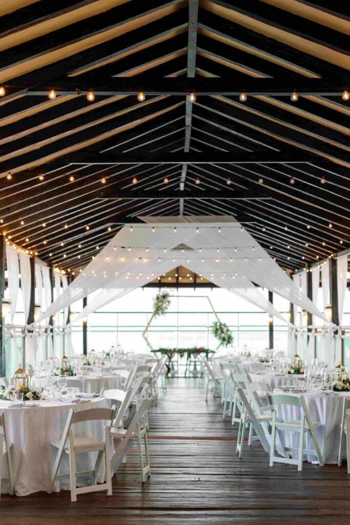 Open-air reception pavilion with string lights and an ocean view at a destination wedding venue